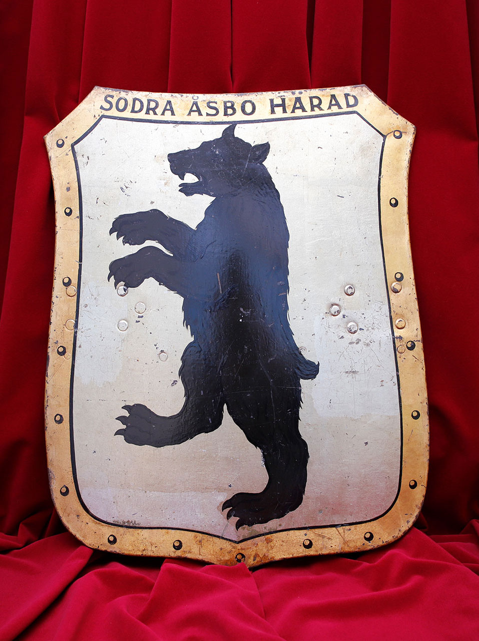 Grå sköld med guldram och svart björn. Överst står texten "Södra Åsbo härad".